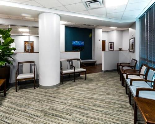 Interior rendering of waiting area. Chairs line the walls.