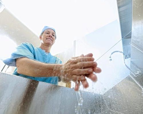 Photo of medical staff washing their hands. View from inside sink looking up.