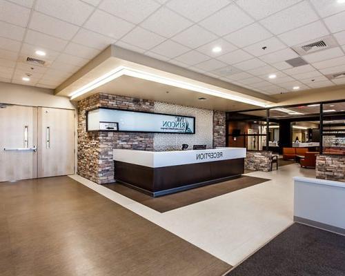 Reception desk of the TMC Rincon Health Campus. Rock wall with large sign with logo are behind the desk.